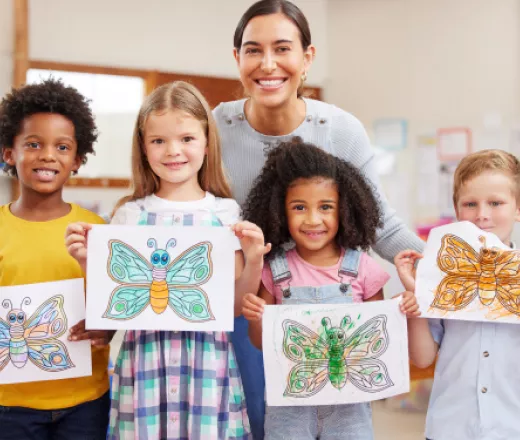 Teacher smiling with kids who made butterfly art in preschool